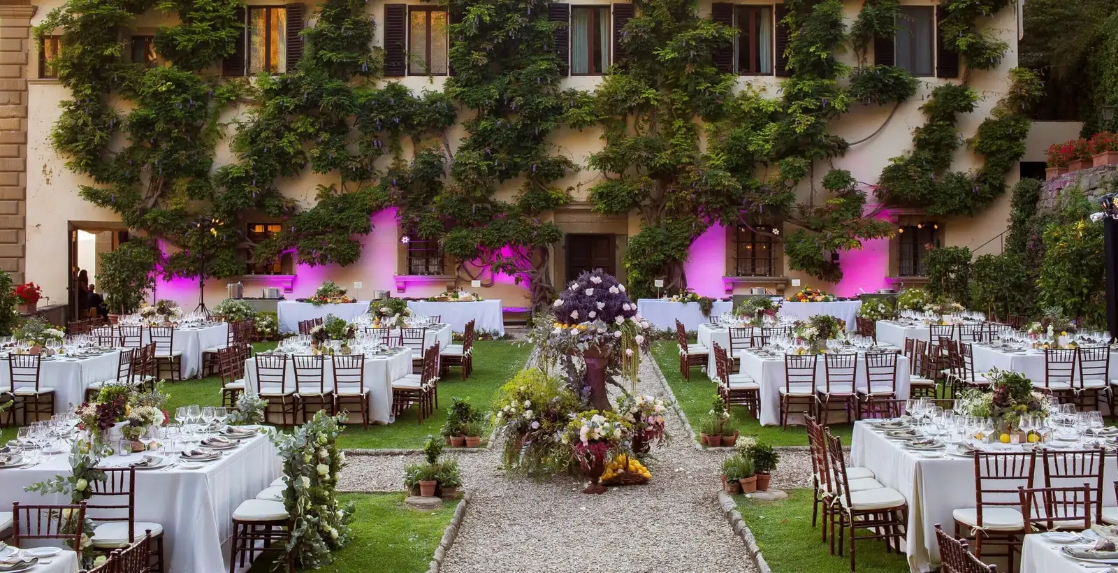 Wedding tables laid in a wisteria-covered villa courtyard, a wedding venue in Italy